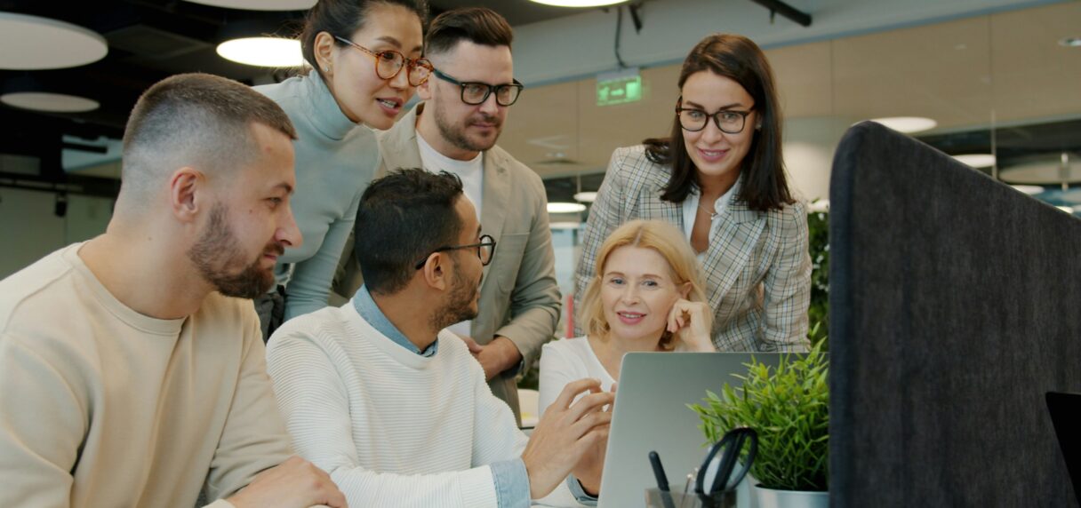 Team discussing a project around a laptop in an office