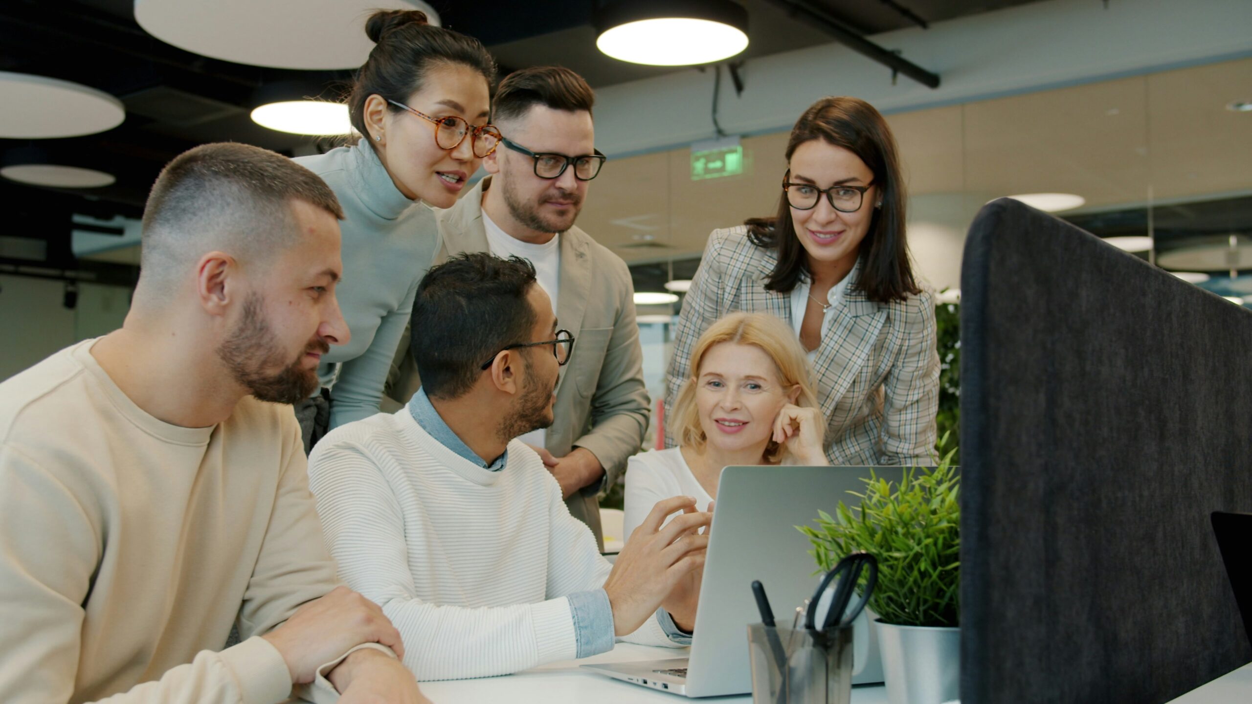 Team discussing a project around a laptop in an office
